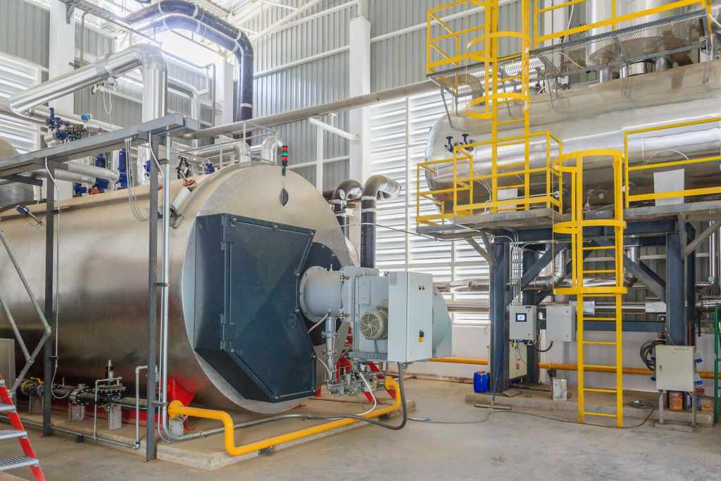 Large industrial boiler with a yellow service catwalk in a mechanical room